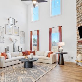 Family room with cathedral ceiling, couch and chair seating area and stone fireplace at DRB Homes The Grange community