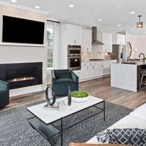 Living room with luxury vinyl wood flooring, fireplace and open concept floorplan to kitchen  in the DRB Homes Westphalia Town Center Townhomes community