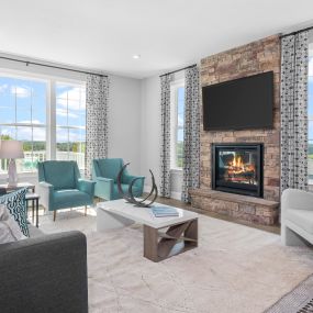 Family room with couch and three chairs, fireplace with TV in DRB Homes Villas at South Park