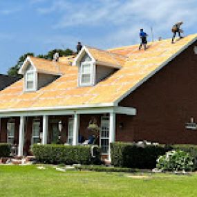Photo of people fixing the roof of a massive house