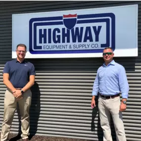 Team members: Vince and Ryan in front of Highway Equipment & Supply Co. logo