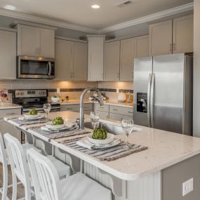 Gourmet kitchen with linen cabinets and a large island in a home in the DRB Homes Cotswold community