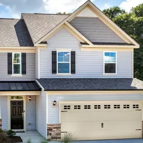 Two story home with gray siding, partial brick stone front exterior with a two car garage in the DRB Homes Cotswold community