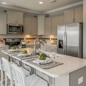 Gourmet kitchen with linen cabinets and a large island in a home in the DRB Homes Cotswold community