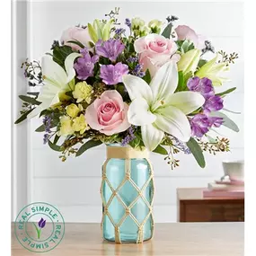 Something special happens when pastel petals come together. Designed exclusively in partnership with Real Simple, our any-day bouquet is highlighted by roses and lilies in pink, lavender and white. Loosely gathered in our new sea green glass jar featuring a handmade macramé cover, its soft, delicate style is a dream for every décor.