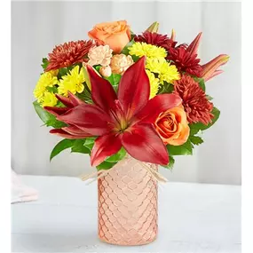 Our colorful bouquet celebrates autumn’s rich beauty. Harvest-toned blooms are loosely gathered with pops of peach for a touch of sweetness. Adding to the charm is our peach quartz mason jar, a textured container designed in a honeycomb pattern and finished with a raffia bow.