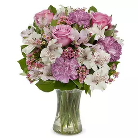 Have you ever seen two colors complement each other so perfectly? Lavender and white are the graceful focal points of this artistic arrangement featuring an exquisite mix of alstroemeria, roses, carnations, and waxflower in a clear gathering vase.