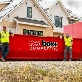 elite dumpster at job site with workers