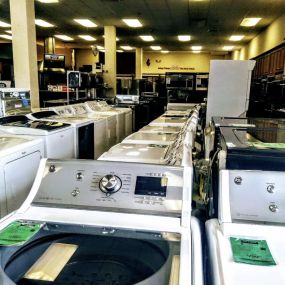 laundry appliance showroom with various white washing machines on display in a row