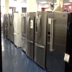 Multiple refrigerators on display lined up in a row with blue flooring