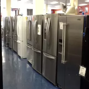 Multiple refrigerators on display lined up in a row with blue flooring