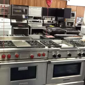 Kitchen showroom with stainless steel wolf ranges in display and more ranges in the back