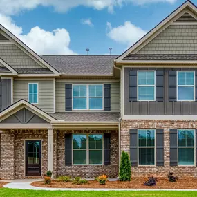 Two story home with brick, tan and grey siding in DRB Homes Kingston Community