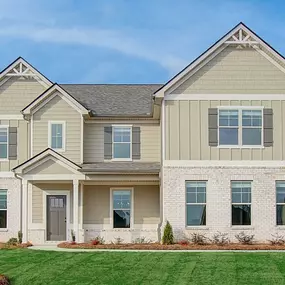 New construction 2-story home with tan brick and siding in DRB Homes Rowland Place community.