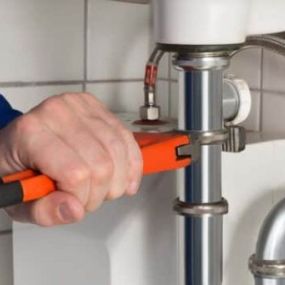 plumber using pipe wrench to make adjustments under a sink