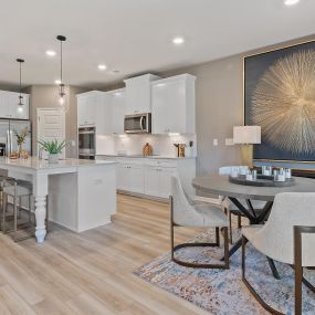 Kitchen with white cabinets and island and dining room in DRB Homes Flakes Mill Community