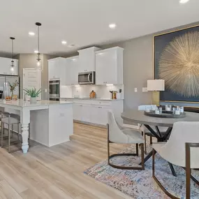 Kitchen with white cabinets and island and dining room in DRB Homes Flakes Mill Community