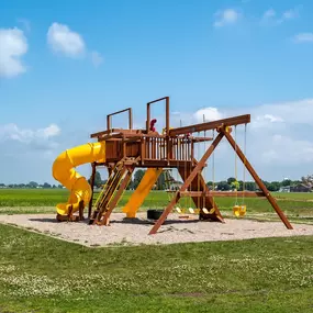 a man sitting on a large yellow swing set in the middle of a grassy field Prairie Crossing Townhomes, Dilworth