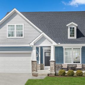 2 Story single family home with blue and gray siding, front porch with stone accents and 2 bay garage in the Aspen II home plan in DRB Homes Deerfield Preserve community