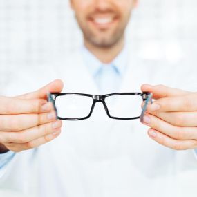 Optometrist handing over a pair of glasses.