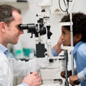 Child receiving an eye exam through a slit lamp