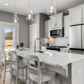 Kitchen with white cabinets, stainless steel appliances and large island in the Litchfield Home Plan at DRB Hickory Heights community