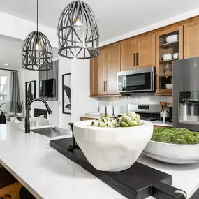 DRB Homes Huntfield Townhomes kitchen with natural wood cabinets, stainless steel appliances and white island.