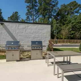 two grills and a picnic table in front of a building