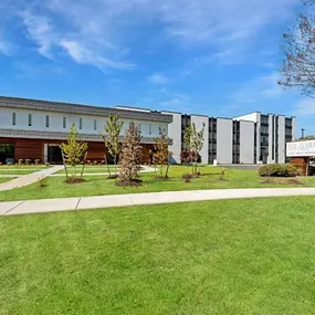 the front of a building with a lawn and trees in front of it