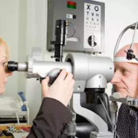 women eye doctor checking old mans eyes