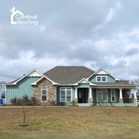 Home with a new asphalt shingle roof and green/blue siding.