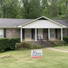 Ranch house featuring a Cardinal Roofing sign in the front yard