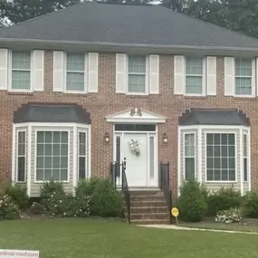 Brown brick-colored home with white accent double-hung windows