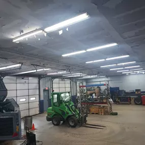 Interior view of the service shop showing active repair bays, machinery, tools, and overhead lighting
