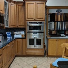 kitchen showroom with wooden cabinetry, tile flooring,  and two built in stainless steel wall ovens