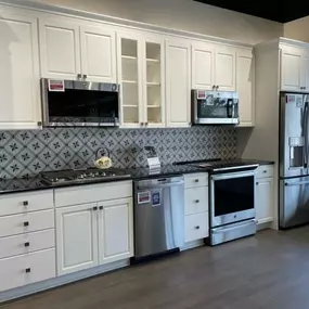 kitchen display with white cabinetry, stainless steel kitchen appliances, and blue tile backsplash