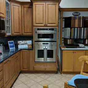 kitchen showroom with wooden cabinetry, tile flooring,  and two built in stainless steel wall ovens