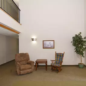 a living room with two chairs and a table and a potted plant