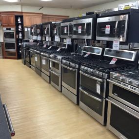 Various dark kitchen ranges lined up for display with light wooden flooring