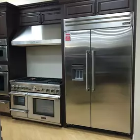 kitchen display with a stainless steel refrigerator, a stainless steel range, and dark cabinets