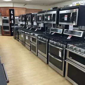 Various dark kitchen ranges lined up for display with light wooden flooring