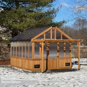 This custom-built cedar greenhouse pavilion by Prestige Renovation showcases exceptional craftsmanship with its elegant metal roof and full-view polycarbonate panels for year-round gardening.