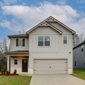 Tan 2 story home with siding and brick front and two car garage in the DRB Homes Village at Waterford community