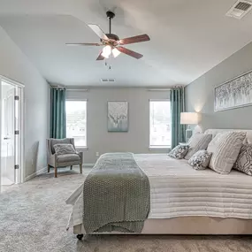 Owner's suit with vaulted ceiling, king bed and two windows and seating area in the DRB Homes Village at Waterford community