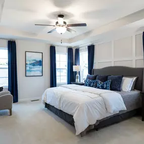 Owners' suite with king side bed, tray ceiling, four windows and ceiling fan in DRB Homes The Village of College Park