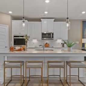 Gourmet kitchen with white cabinets and island in DRB Homes Riverbend Overlook
