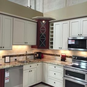 kitchen display with white cabinets, white flooring, a dishwasher, a microwave, and a range