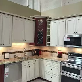 kitchen display with white cabinets, white flooring, a dishwasher, a microwave, and a range