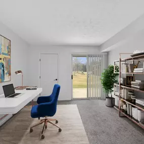A room with a blue chair, a laptop, and a painting on the wall.