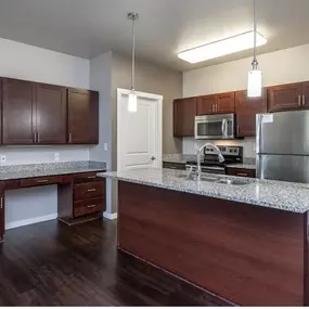 A kitchen with dark wood cabinets and a granite countertop.